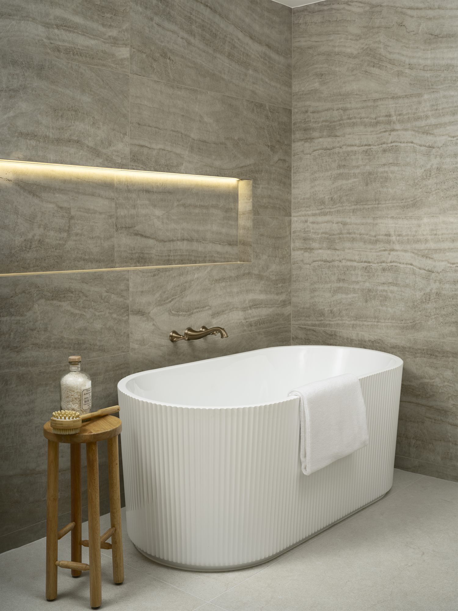 Travertine spa bath with fluted freestanding tub and brushed-gold fixtures
